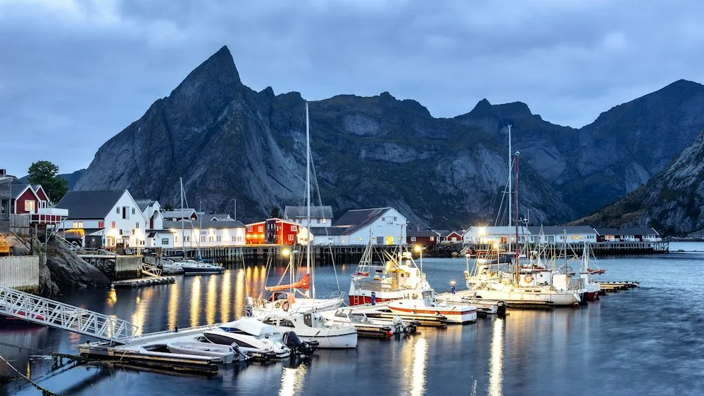 Sailboats moored beneath the mountains in Reine, Norway